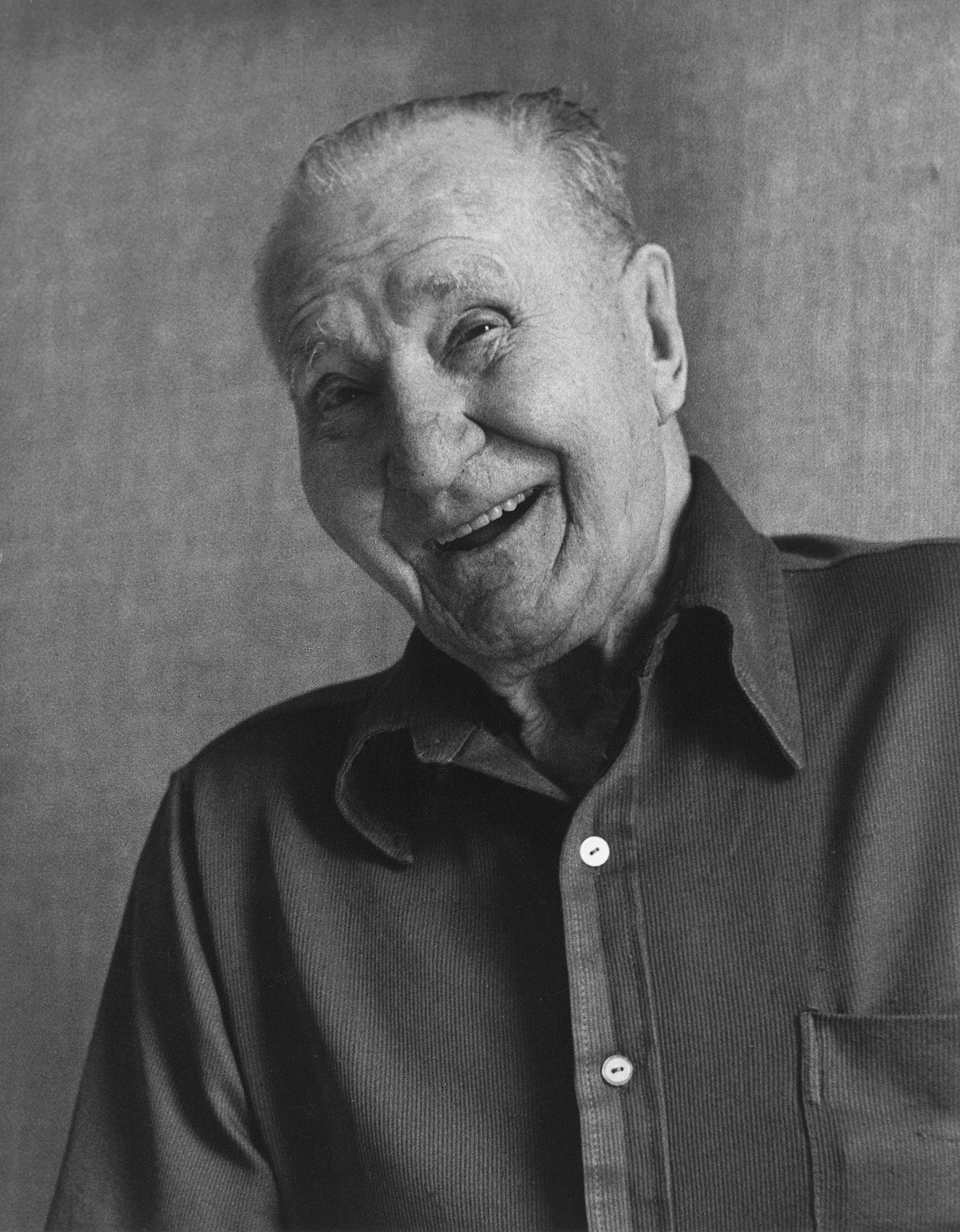 Black and white photo of elderly man portrait with friendly, happy face wearing nice button shirt.