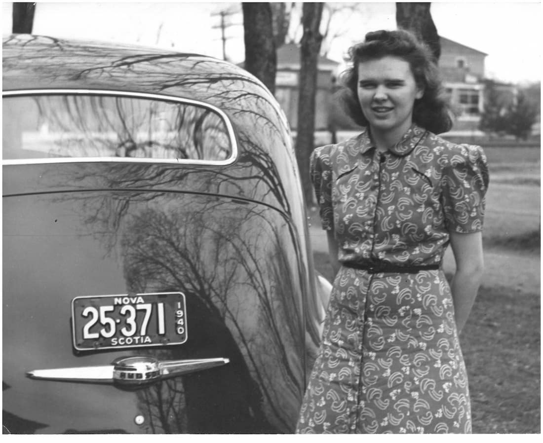 Thelma standing beside an old car with Nova Scotia license plate with year 1940.